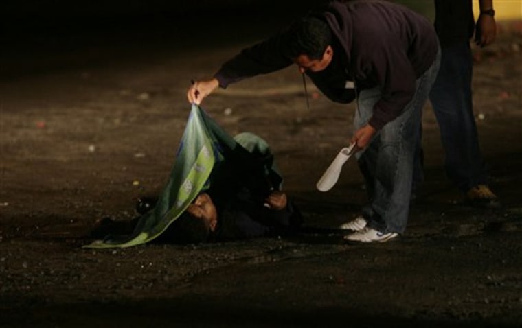 **ADVANCE FOR FRIDAY, MAY 14 ** FILE - In this April 25, 2010 file photo, a police forensic expert examines the body of a slain municipal police officer after a gunfight in Guadalajara, Mexico.  According to the police, two men opened fire after being stopped by two police officers to inspect their car. One police officer was shot dead, one gunman was killed and three others were injured. After 40 years of blood and money, both Mexico and the U.S. governments admit that the War on Drugs is a failure.  (AP Photo/Carlos Jasso, File)